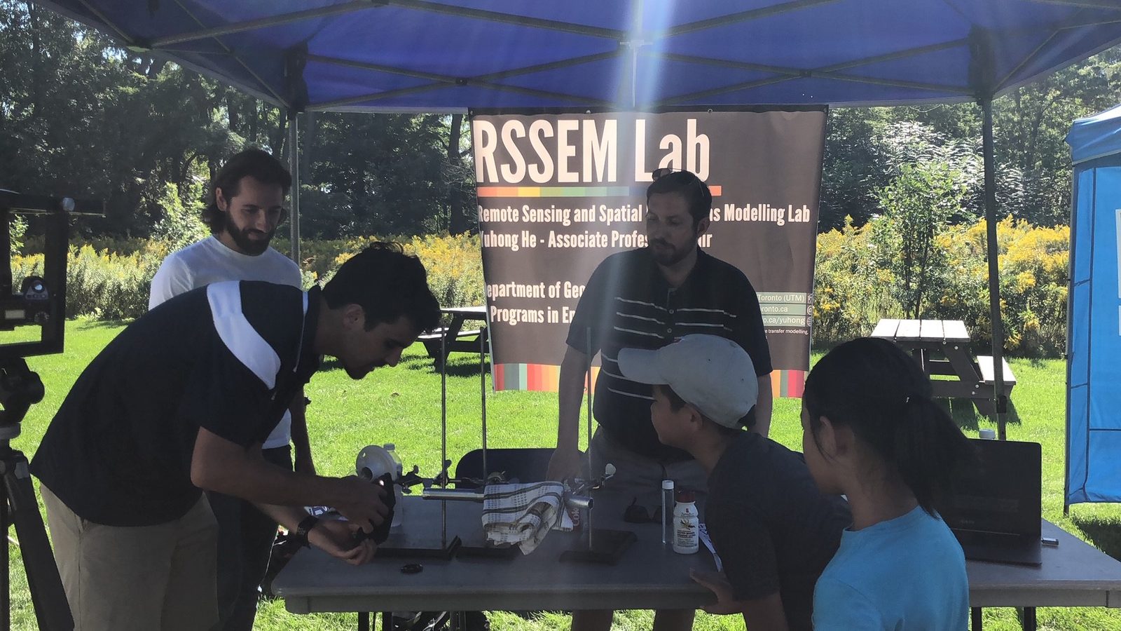 Lab members demonstrating remote sensing equipment at an RSSEM Lab outdoor booth