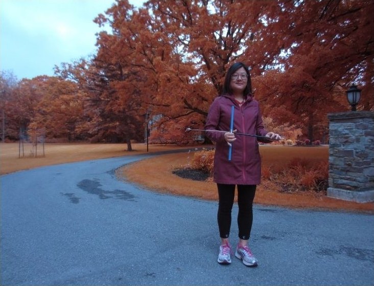 Holding a field instrument on an autumn campus road